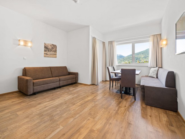 Wohnbereich mit Balkon und Flat-TV im Appartement Tennengebirge